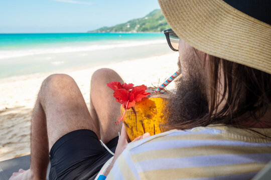 Portrait of a man drinking coconut milk on the beach