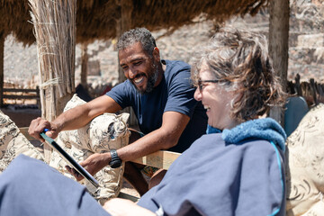 Happy tour guide checking roster list with woman tourist