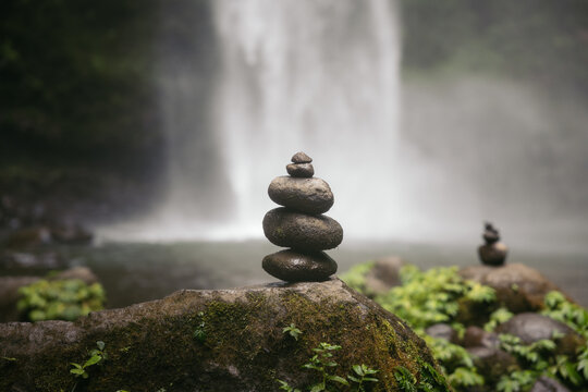 stack of stones balanced in front of a waterfall