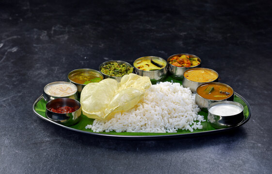 Kerala Veg Thali. Traditional Indian meal served on a banana leaf with rice, curry, various vegetables, and sauces, evoking a sense of culture, authenticity, and culinary diversity.