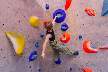 Bouldering climbing athlete woman training at indoor gym boulder climb wall. Teenager fit girl going up having fun in extreme sport hobby. Social media template