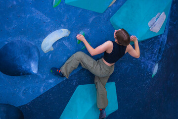 Bouldering climbing athlete woman training at indoor gym boulder climb wall. Teenager fit girl going up having fun in extreme sport hobby. Social media template © Mike Orlov