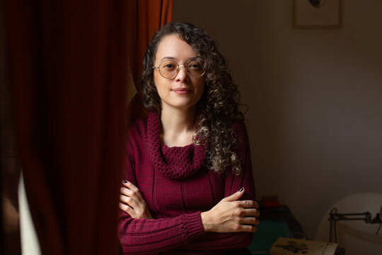 Pensive woman with round glasses looking straight at camera