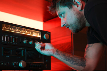Attentive man changing the settings of his stereo sound system 