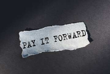 A torn piece of paper with the words pay it forward written on it, symbolizing the concept of doing...
