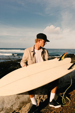 Surfer checks the fins of his retro surfboard before entering the sea