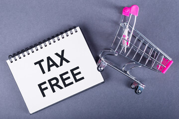 A notebook with TAX FREE text beside a small shopping cart symbolizes duty-free shopping benefits.