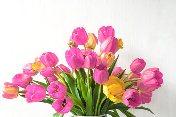 Bunch of red and yellow tulips flowers in vase on white background; Beautiful spring holiday background