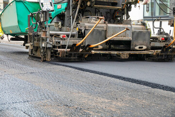 Repair of asphalt road surface - old layer removed and a coating Industrial pavement truck laying new fresh asphalt on construction site.