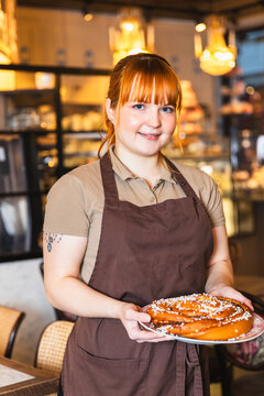 Portrait of waiter serving giant cinnamon bun and looking to camera