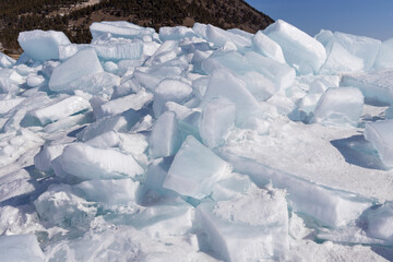 Winter natural background with fragments of blue ice and heaps of pieces of ice floes on Lake...