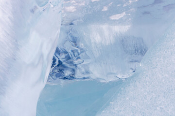 Winter natural background with fragments of blue ice and heaps of pieces of ice floes on Lake...