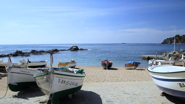 Fishing boats on the beach of Port Bo with the Mediterranean Sea in the background. Calella de Palafrugell, Costa Brava, Catalonia, Spain.