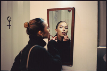 Young woman applying lipstick at home