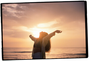 Woman standing with outstretched hands in front of the sea