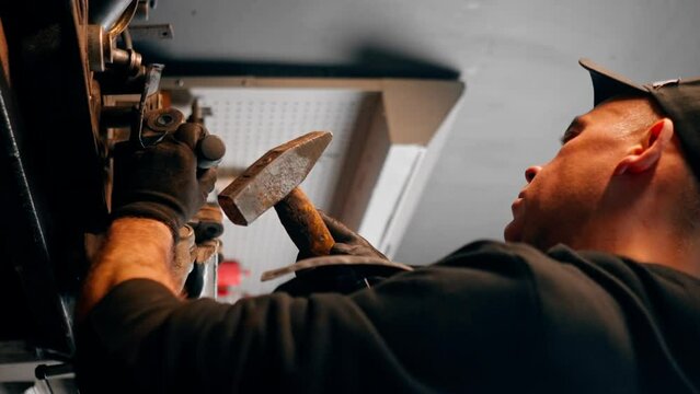 vertical video close up At a service station car mechanic's hands work with a hammer on a car disk