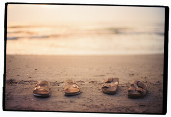 Two pairs of sandals on sand near sea