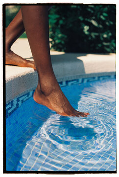 Woman touching water in pool with her foot