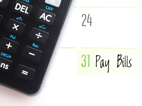 Bill payment day concept: a calendar showing the text "Pay bills" on the 31st and a black calculator