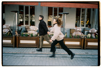 Film photo of a happy couple in love, running through the city street