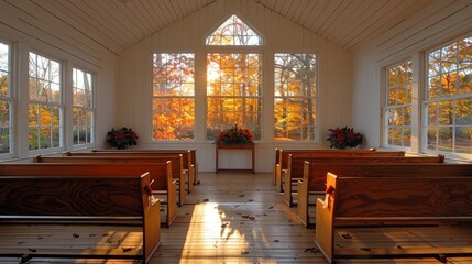 View inside a tranquil small church with wooden benches and vibrant autumn trees visible through large window