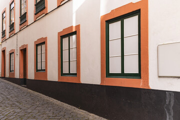A white and orange stucco building on a cobbled street on Terceira Island, Azores. - Powered by Adobe
