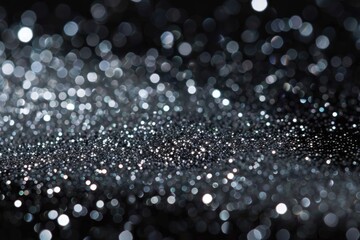 A close-up shot of silver glitter spread across a solid black background, highlighting the shimmering details and contrast.