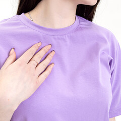 Young woman in cotton lilac T-shirt on white background. Collar closeup