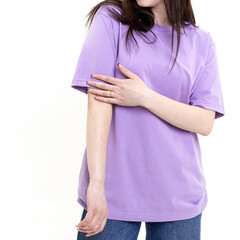 Young woman in a long lilac T-shirt and blue jeans on white background