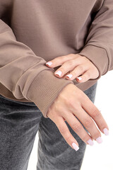 Woman in brown long sleeve shirt. Cotton sweatshirt and jeans on white background. Soft elastic band on sleeve closeup