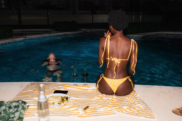 Diverse friends enjoying night swimming pool 