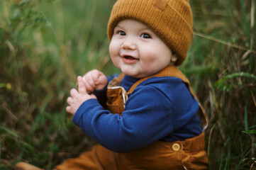little infant baby boy sitting in grass in autumn