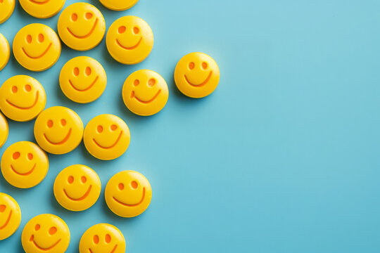 Yellow smiley face pills scattered on a bright blue background, depicting the concept of happiness and mental health treatment