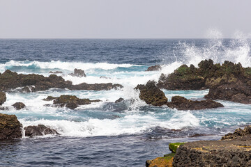 Fototapeta premium Surf crashing on lava rocks on the shore of Terceira Island, Azores.