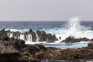 Surf crashing on lava rocks on the shore of Terceira Island, Azores.
