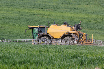 Farmer using a self propelled crop sprayer in a field in early spring.