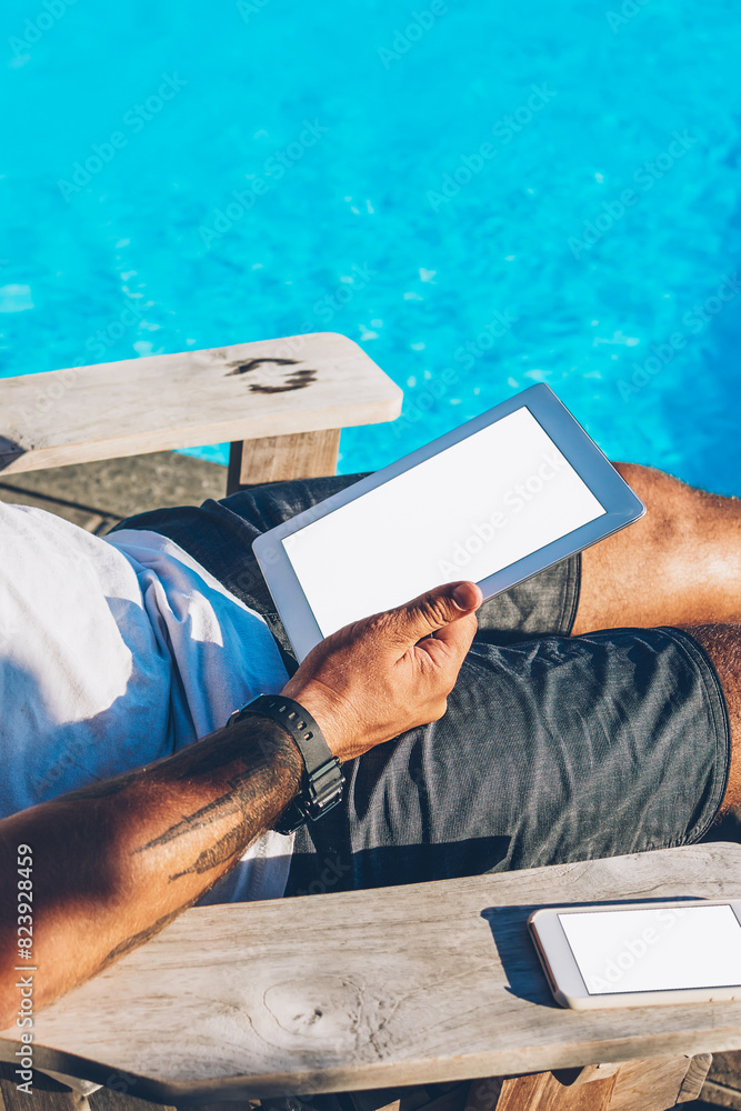 Poster young man in sunglasses drinking cocktail while reading business news on internet websites and worki