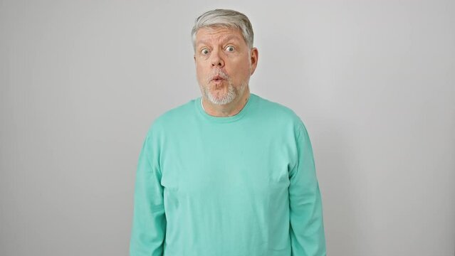 Amazed middle age man with grey hair in casual clothes, scared expression, open mouth in disbelief against isolated white wall - big surprise shock!