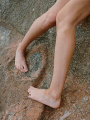 Legs of Paradise: A Stunning Brunette Woman in Sexy Swimwear Poses Happily on a Beach Rock, Graced by the Summer Sun and Serene Ocean.