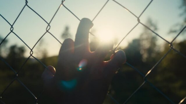Abstract close-up of a hand grabbing the fence. Concept of Division, Boundary, Freedom, Despair, Anxiety, Hopelessness, Immigration, Refugee Struggle, Despair, Discrimination, Separation, Depression