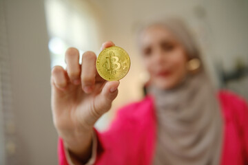 A woman is holding a gold coin in her hand. The coin has a symbol on it that looks like a letter