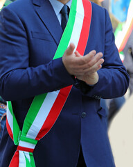 mayor of a city in Italy wearing the national tricolor green white and red sash during meeting