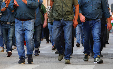 men strolling down city streets, their legs clad in blue denim jeans are the only visible portion of their bodies