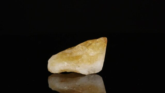 Polished mineral stone citrine rotates in a circle on a black background