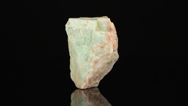 Polished mineral stone Amazonite rotates in a circle on a black background