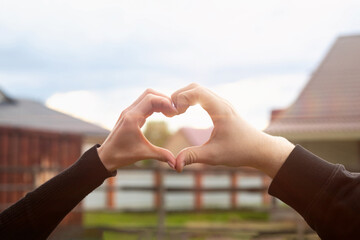 A couple of lovers make a heart gesture with their fingers .