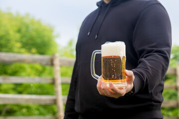 A man shows a full glass of beer and foam.