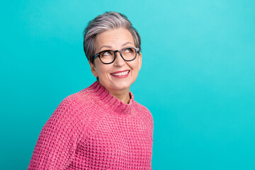 Photo of cheerful woman with gray hair dressed knitwear sweater in glasses look at sale empty space isolated on teal color background