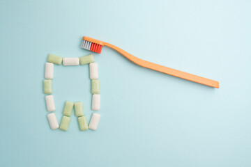 Toothbrush and chewing gum lie on a colored background. Time to brush your teeth. Top view, flat lay. Dental health concept
