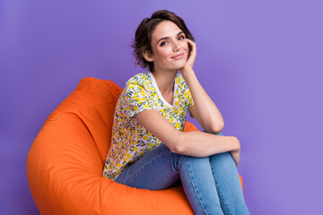 Photo of pretty young woman sit comfy bag wear t-shirt isolated on violet color background